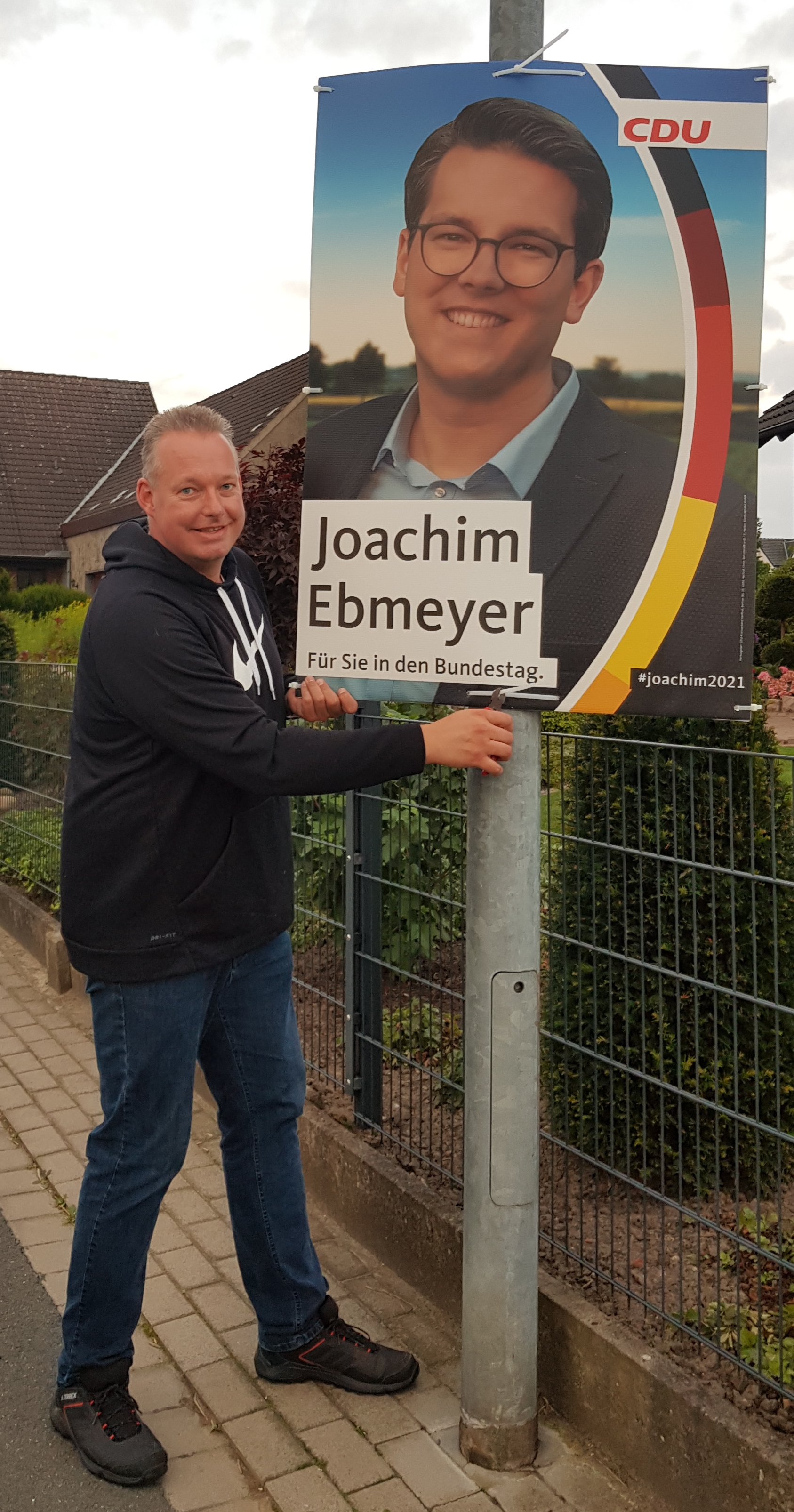 Marco Mhle bringt Plakate an die Laternenmasten an